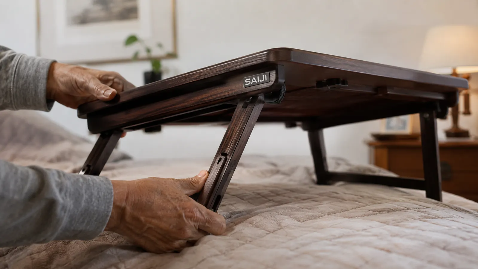 Hands adjusting the folding legs of a wooden lap desk before setting it over a lap in bed
