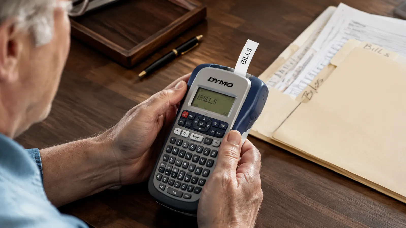 Hand holding the DYMO label maker printing a label for a file folder