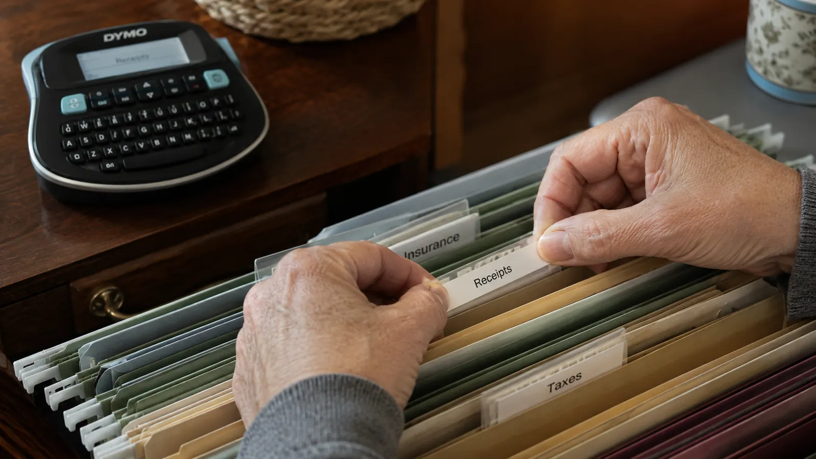Hand pressing a freshly printed label onto a hanging file folder