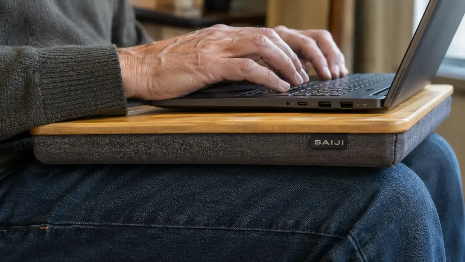 Close view of hands typing comfortably on a laptop propped on a tilted lap desk